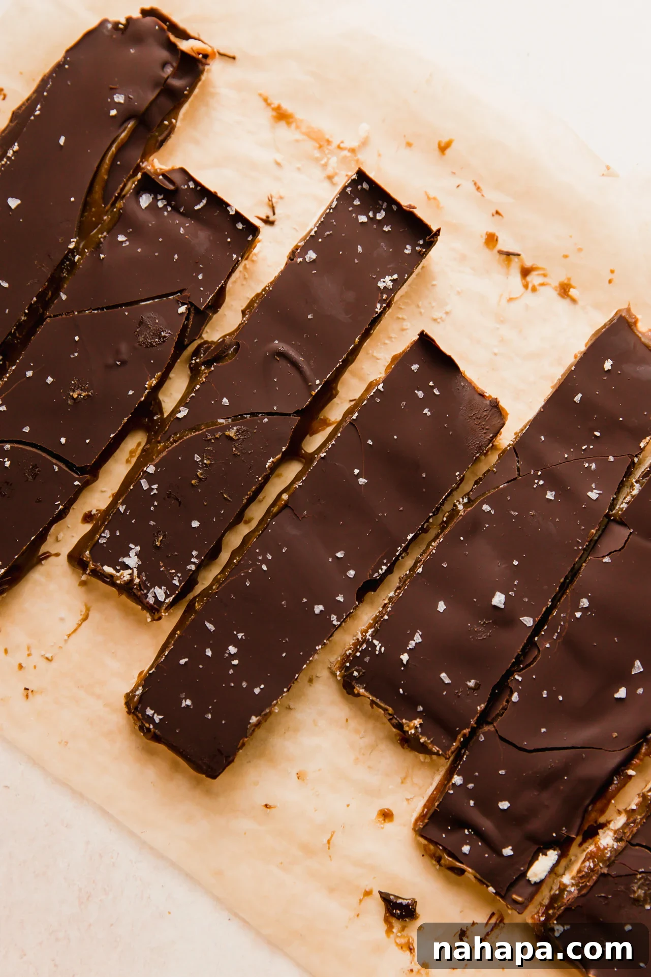 Homemade Gluten-Free Caramel Shortbread Bars 7 Twix bars sliced on a piece of parchment paper.
