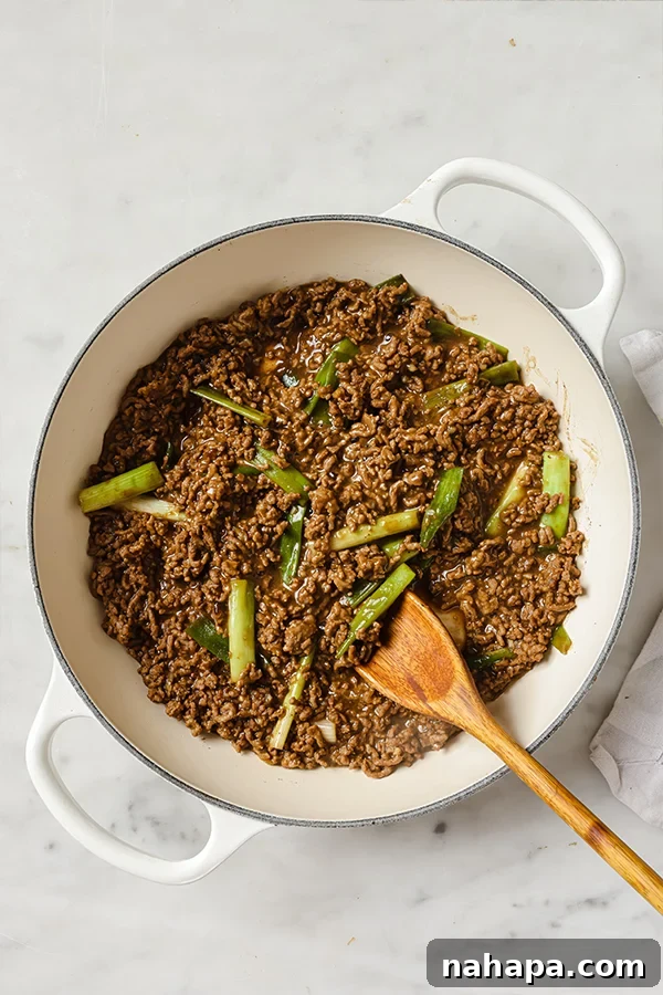Close-up of Mongolian Ground Beef in a skillet, garnished with fresh green onions.