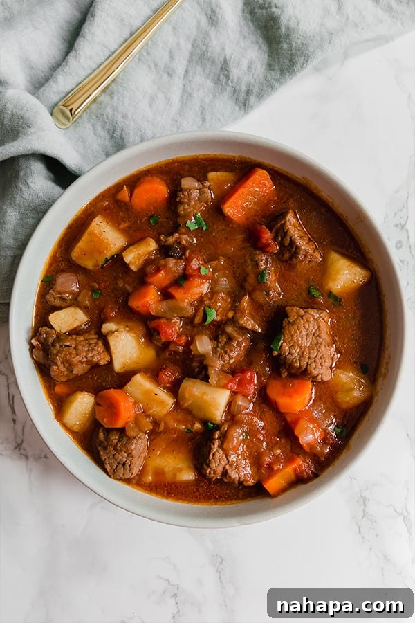 Close-up of Greek Tomato Beef Stew bubbling in a pot, showcasing tender beef and vibrant vegetables.