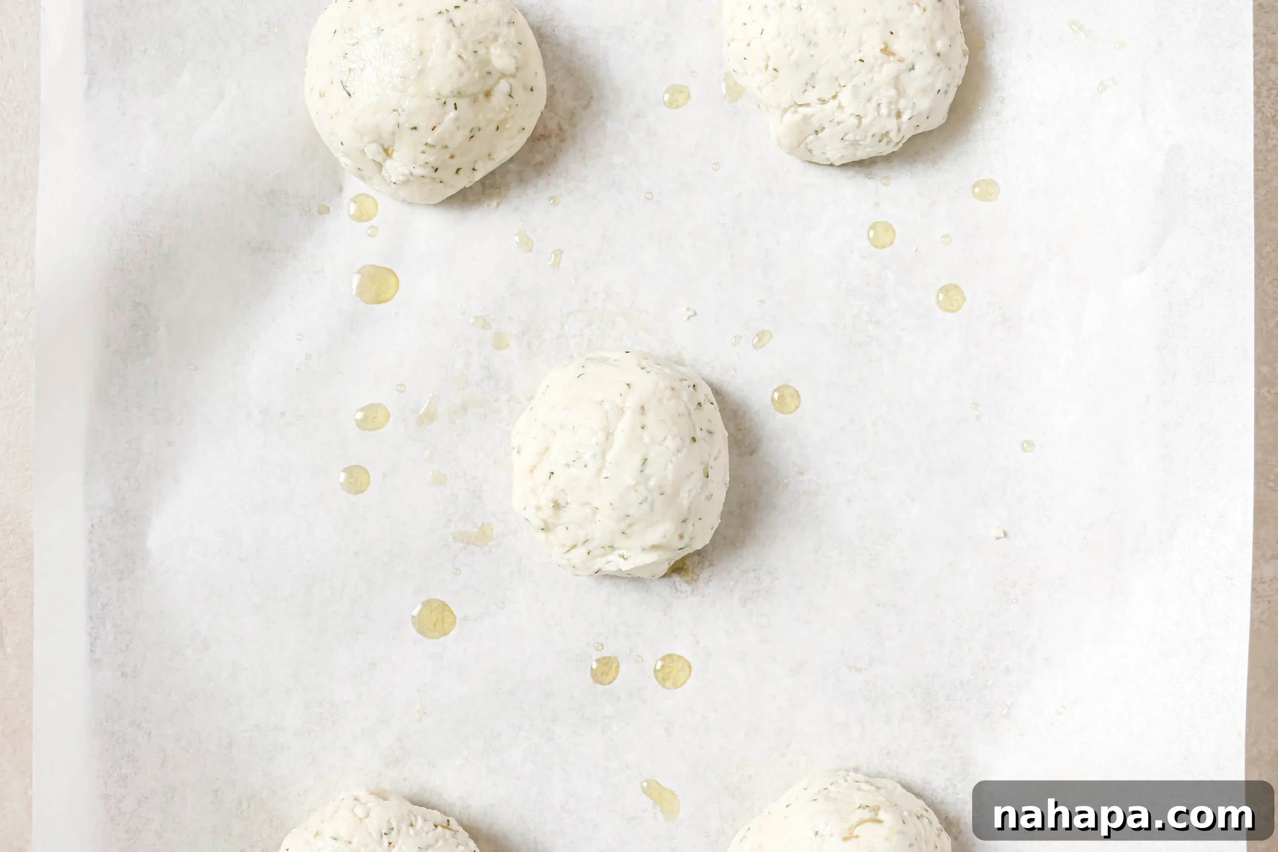 Five uncooked bread rolls on a baking sheet
