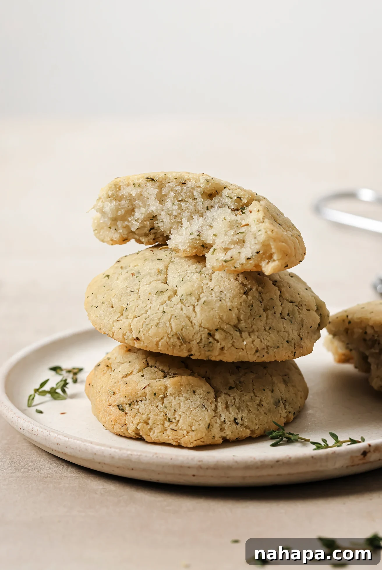 Stack of three garlic & herb rolls on a white plate with thyme on the side.