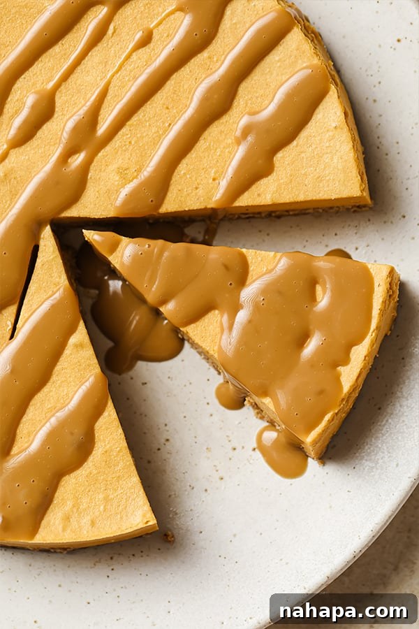 AIP Paleo Autumn Salted Caramel Pumpkin Cheesecake 6 Several slices of dairy-free salted caramel pumpkin cheesecake are arranged on a white plate, each topped with a generous drizzle of homemade caramel and a sprinkle of salt flakes.