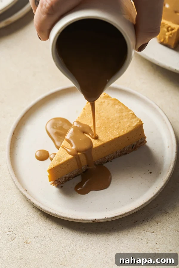 AIP Paleo Autumn Salted Caramel Pumpkin Cheesecake 7 A rustic overhead shot of a whole dairy-free salted caramel pumpkin cheesecake, topped with caramel and salt flakes, placed on a wooden board.