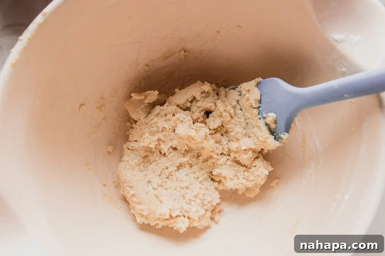Spritz cookie dough in a bowl with a spatula, ready to be transferred to the cookie press.