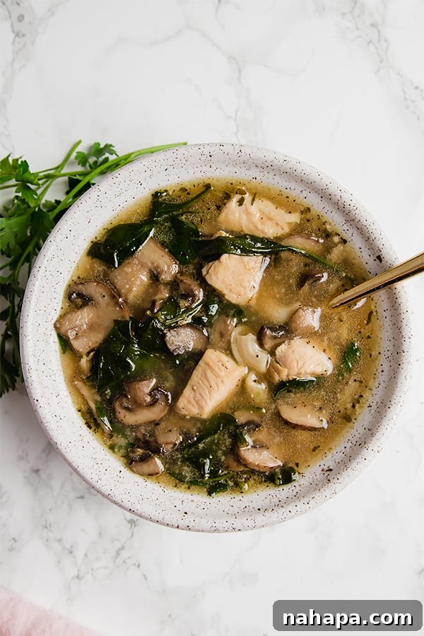 A close-up shot of a bowl of Chicken Marsala Soup, steaming hot and garnished.