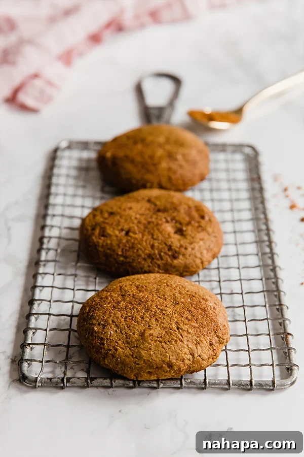 Close-up of freshly baked Paleo Gingersnap Cookies cooling on a wire rack, showing their crinkled tops.