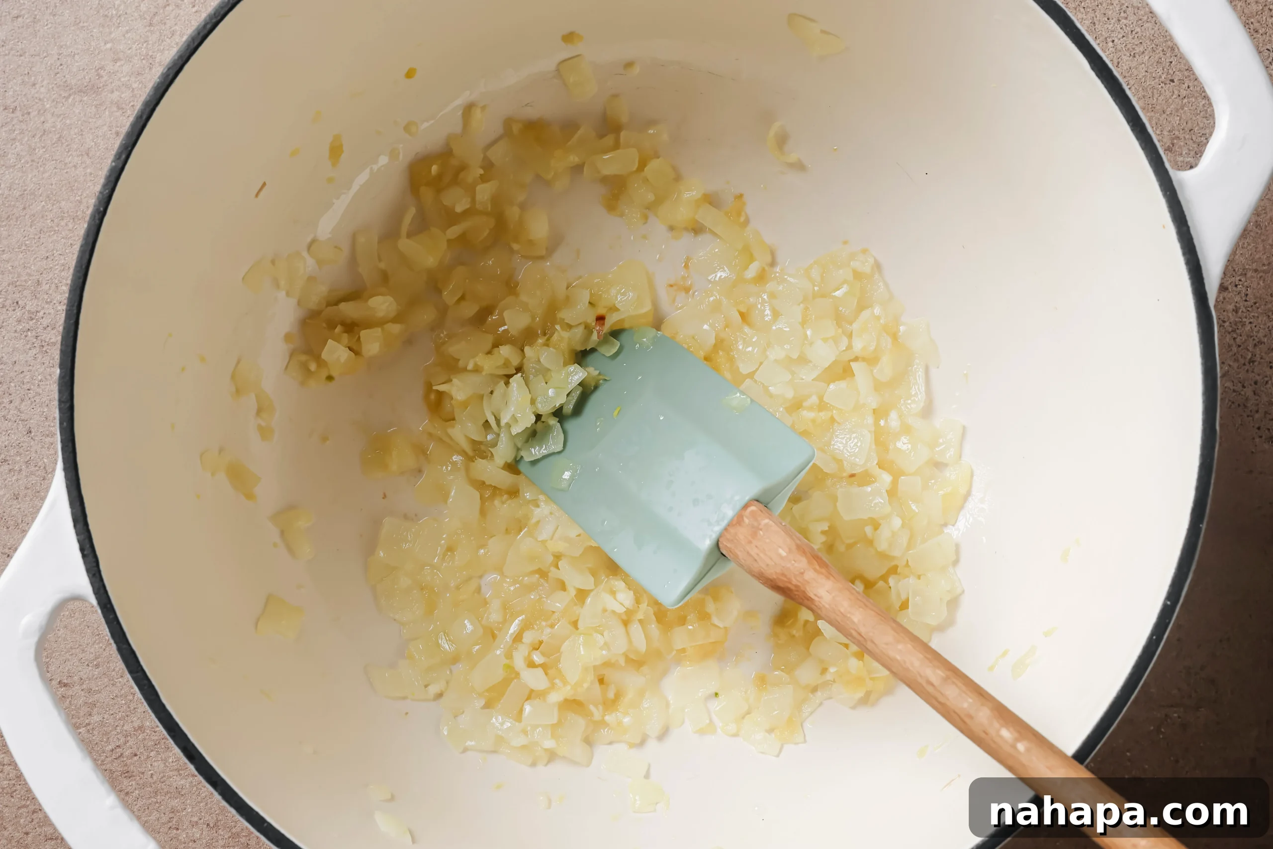 Diced onions gently sautéing in a pot with coconut oil, turning translucent and releasing their sweet aroma.