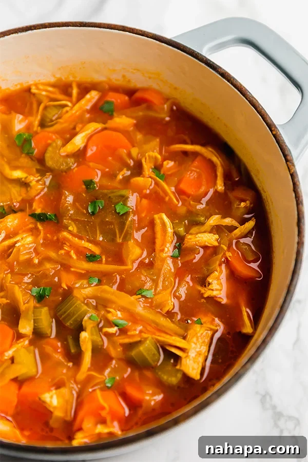 A steaming bowl of vibrant Turmeric Cabbage Soup garnished with fresh parsley.