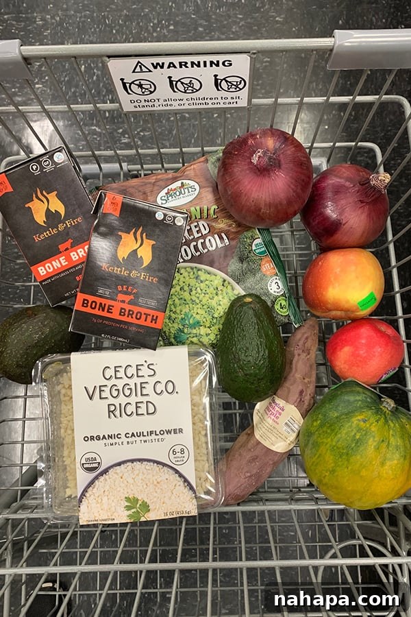 Budget Paleo: Smart Shopping at Sprouts 4 A full shopping cart with a variety of healthy groceries including fresh produce, bone broth, and organic apples.