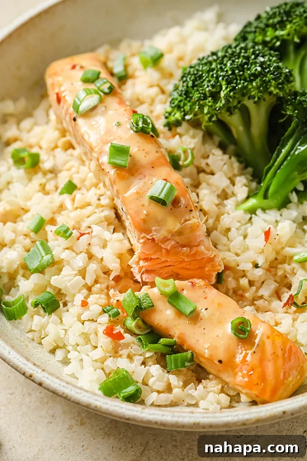 Clean Eating Bang Bang Salmon Bowls 5 Bang Bang salmon in a bowl, cut in half, showcasing the sauce and flakes
