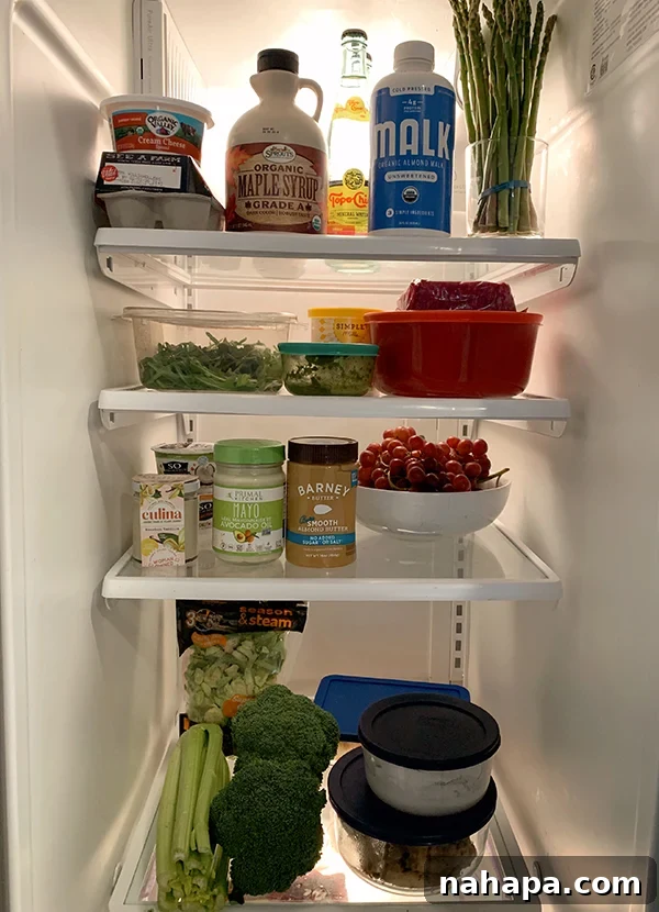 An open refrigerator revealing an organized array of fresh organic produce, healthy beverages, and various dairy-free and clean-ingredient staples from Sprouts.