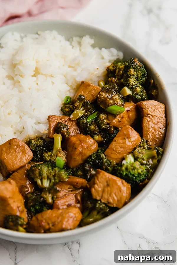 Easy 20-Minute Chicken and Broccoli Stir-Fry 3 A close-up shot of a healthy chicken and broccoli stir fry, glistening with sauce, served in a white bowl