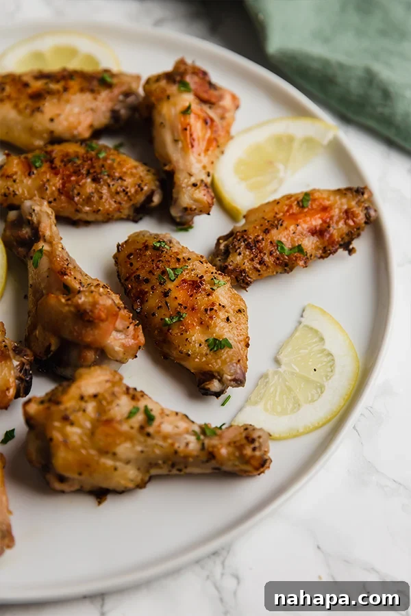 Zesty Lemon Pepper Wings 4 A plate of baked Lemon Pepper Chicken Wings garnished with fresh parsley and lemon slices.