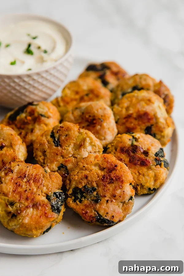 Creamy Spinach Artichoke Chicken Sweet Potato Bites 5 A plate of Spinach and Artichoke Sweet Potato Chicken Poppers with a dipping sauce