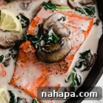 Salmon florentine in a pan topped with mushroom and spinach.