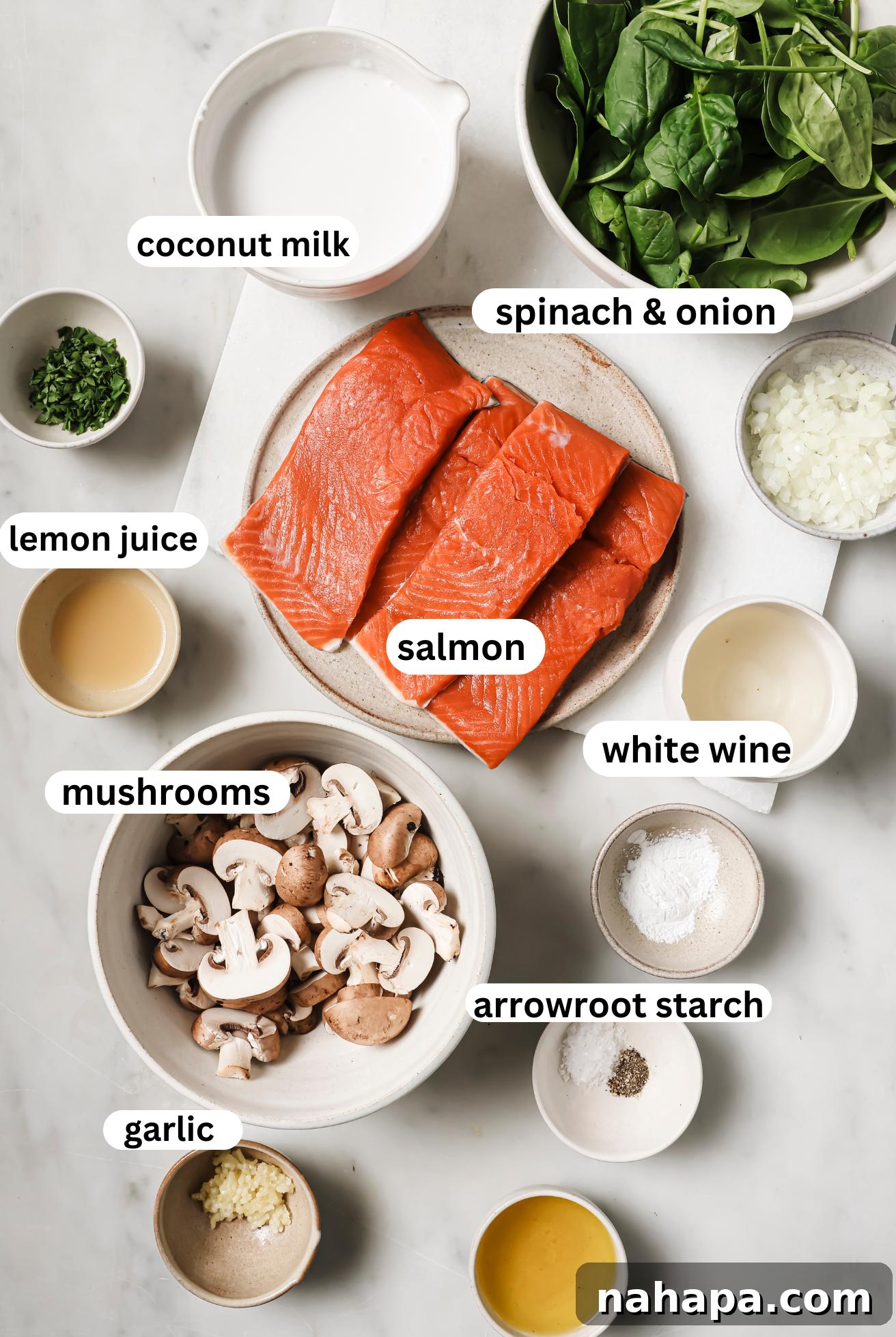 All the ingredients for Creamy Salmon Florentine neatly arranged in bowls on a white surface.