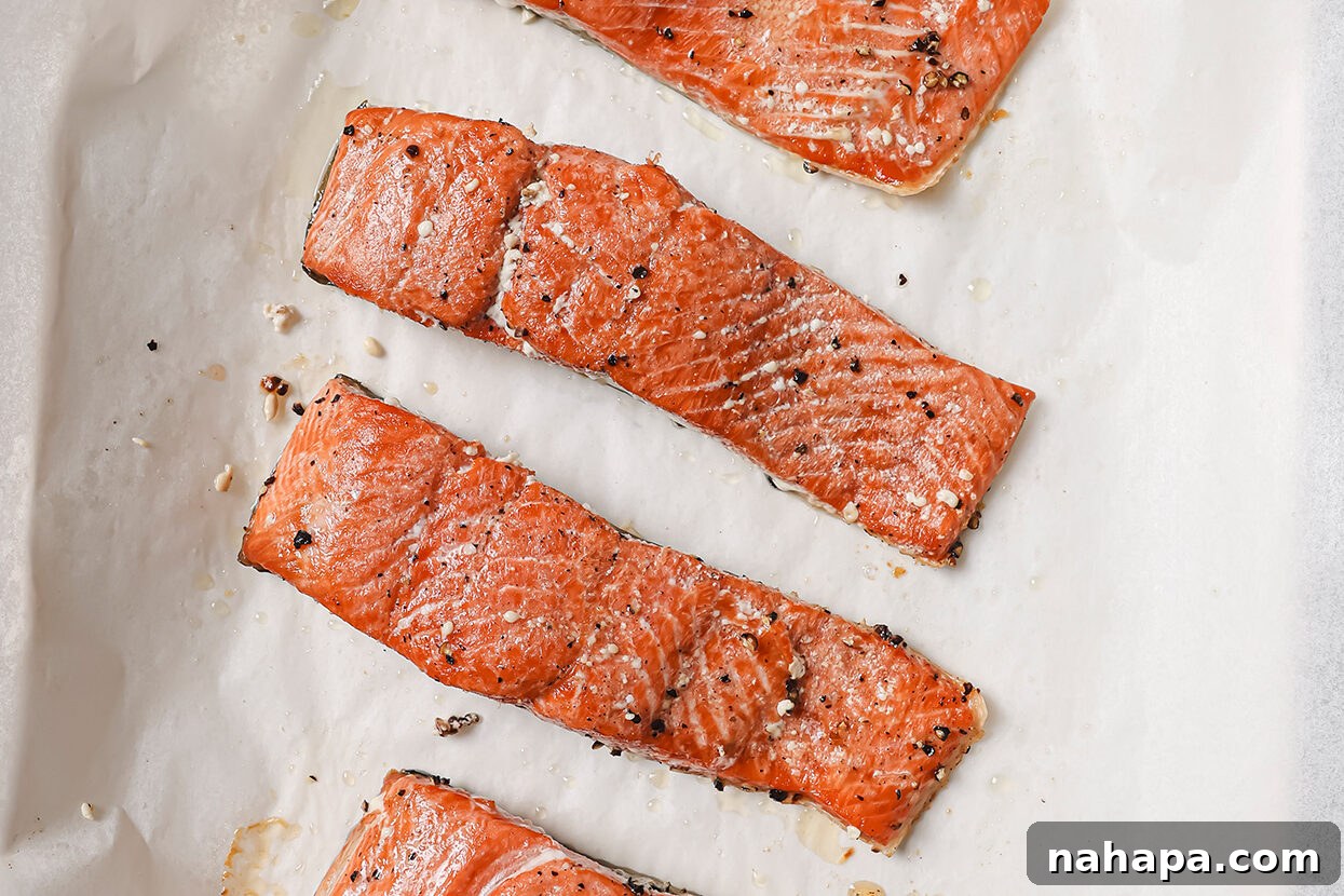 Cooked salmon fillets with crispy skin, removed from the pan and resting on parchment paper.