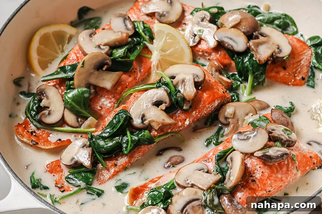 Fully cooked creamy salmon Florentine in a pan, garnished with mushrooms, spinach, and lemon slices.