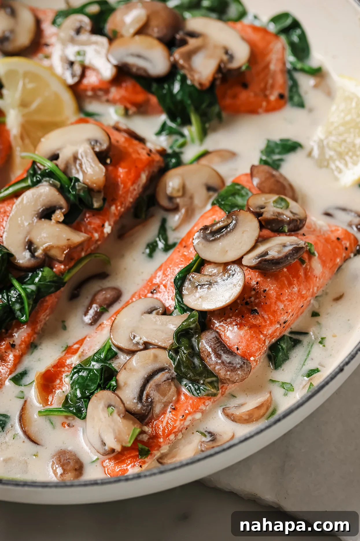 Close-up of creamy salmon Florentine in a pan, richly coated with mushroom and spinach sauce, ready to be served.