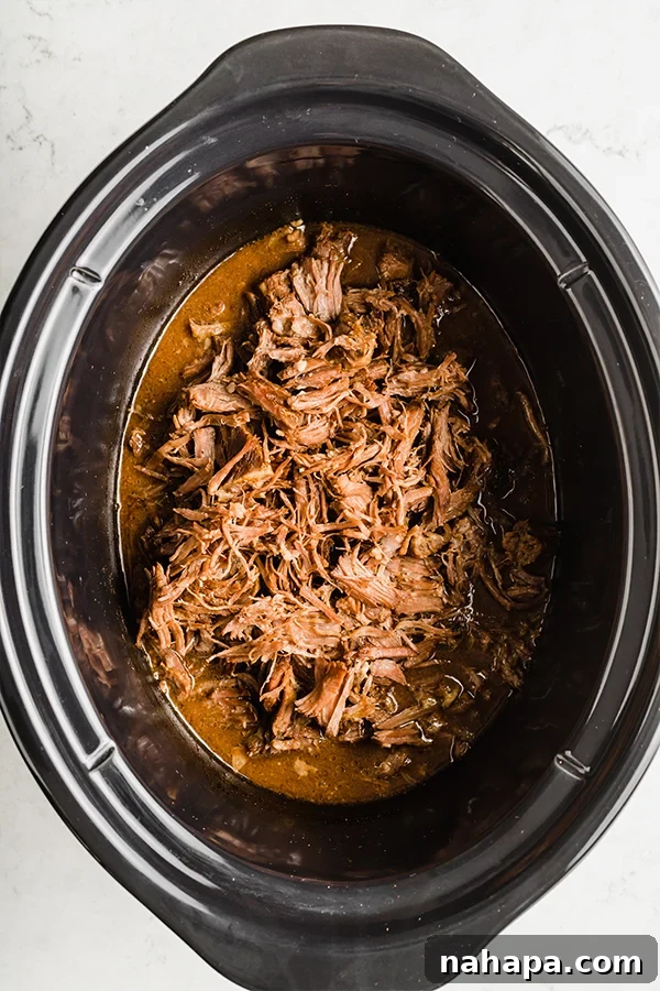 Shredded beef simmering in a slow cooker, ready to be served.