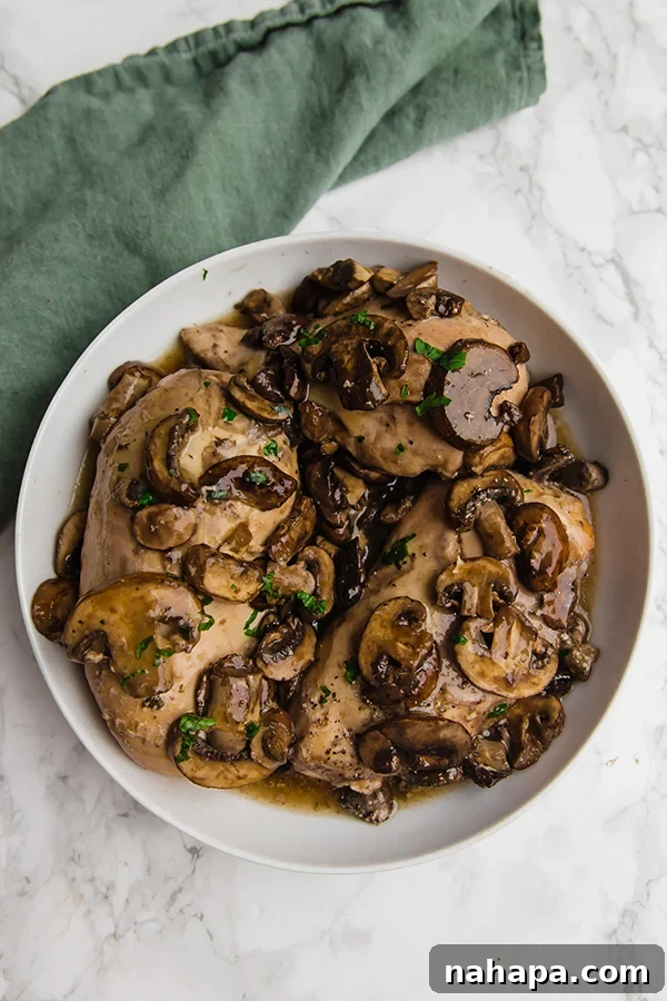 Ingredients for Slow Cooker Chicken Marsala laid out on a cutting board, including chicken, mushrooms, and fresh herbs.
