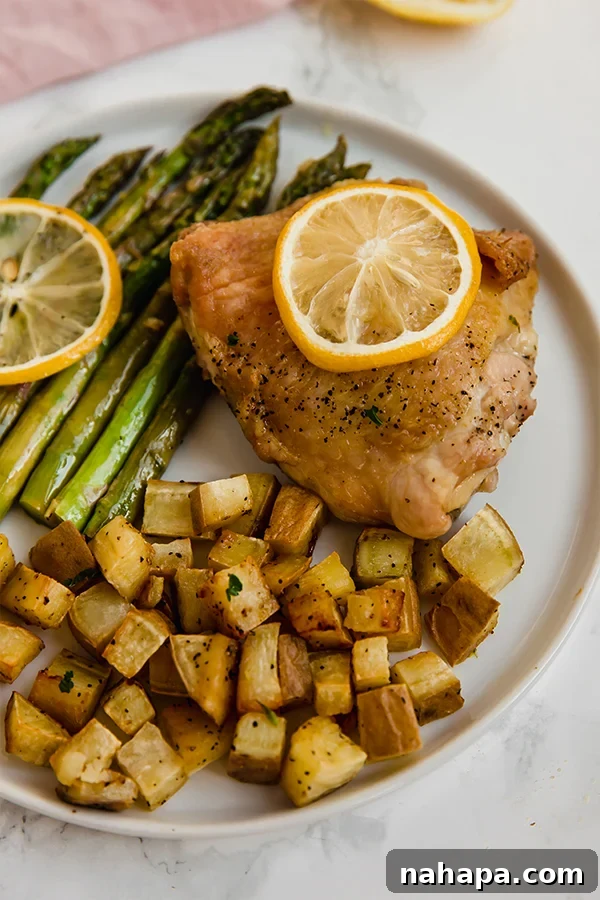 Effortless Lemon Garlic Chicken and Asparagus 4 Close-up of a plate with roasted lemon chicken, asparagus, and sweet potatoes, garnished with fresh parsley