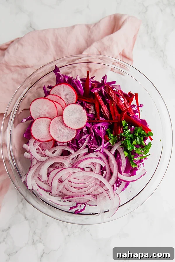 Purple coleslaw in a large mixing bowl with fresh ingredients.
