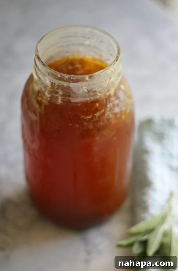 A jar of homemade gut-healing bone broth with fresh herbs and spices.
