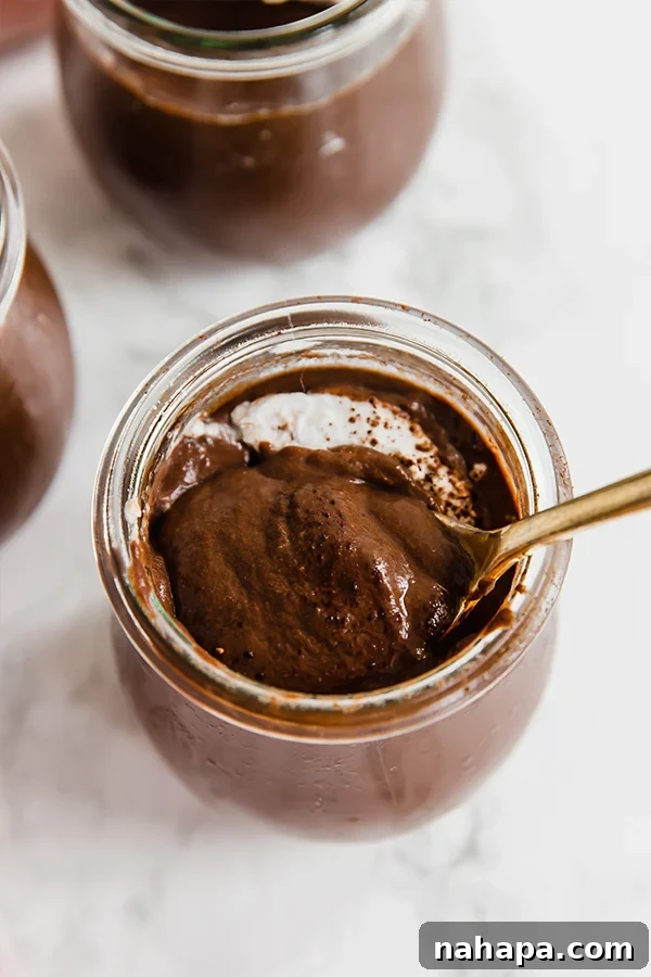 Chocolate pudding in glass jars, garnished with fresh berries.