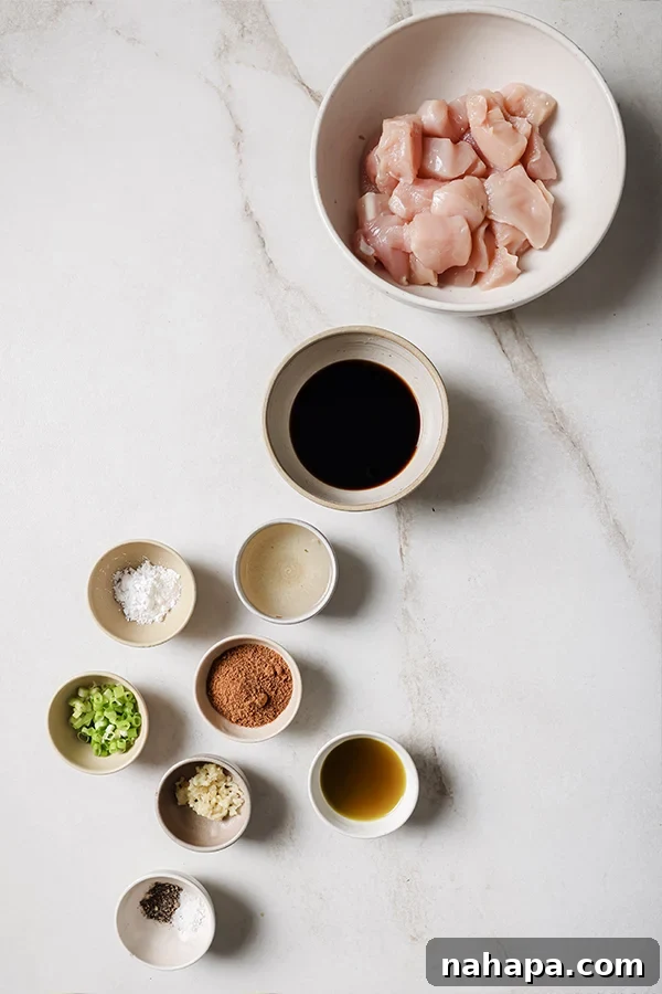All the wholesome ingredients for healthy bourbon chicken, including chicken, coconut aminos, apple juice, and spices, are neatly laid out on a countertop, ready for preparation.