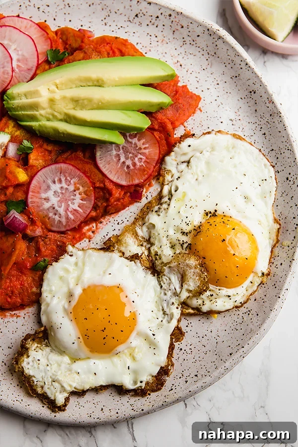 Close-up of vibrant Plantain Chilaquiles with fresh toppings and an egg