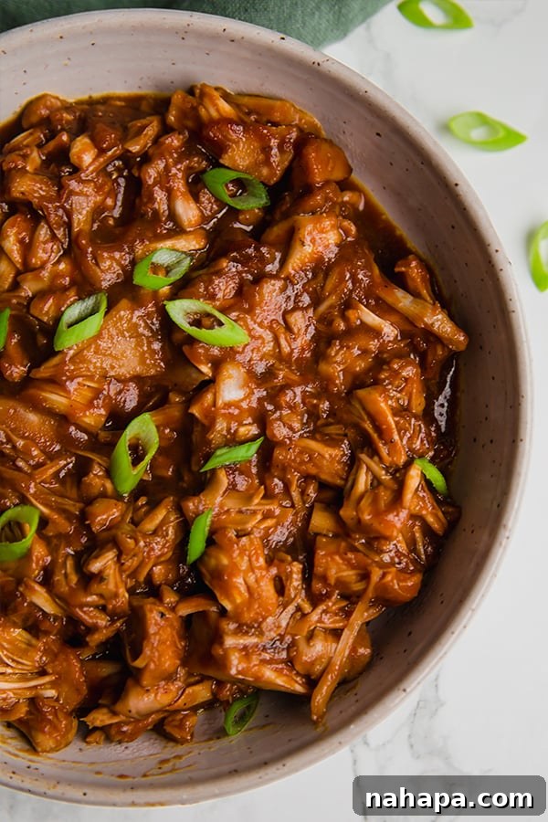 Smoky Pulled Jackfruit 6 A vibrant bowl of BBQ jackfruit, seasoned to perfection, resembling pulled pork with fresh green onions scattered on top.