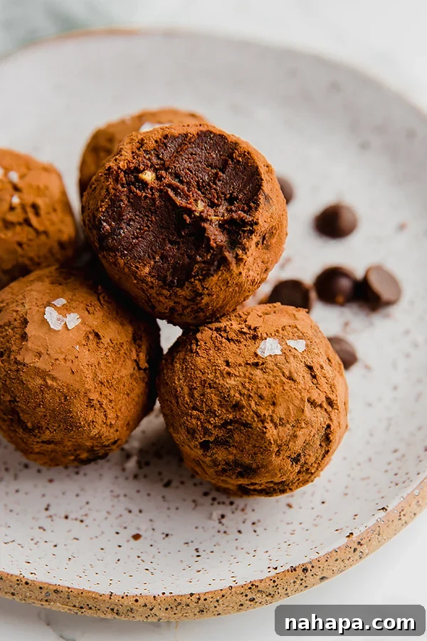 Decadent Protein-Packed Chocolate Avocado Truffles 4 Three Chocolate Avocado Protein Truffles stacked on a plate, garnished with sea salt