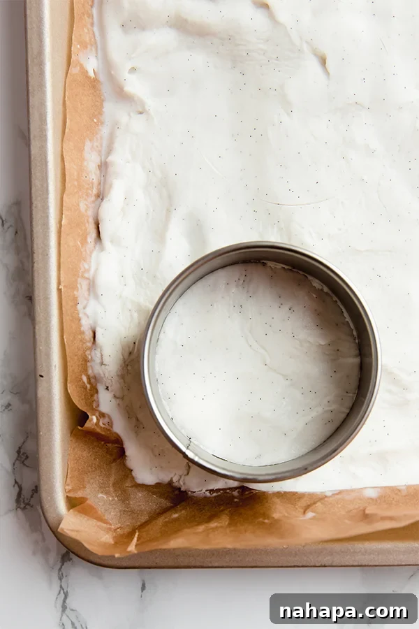Scooping softened dairy-free ice cream onto parchment paper for flattening and freezing, next to a biscuit cutter
