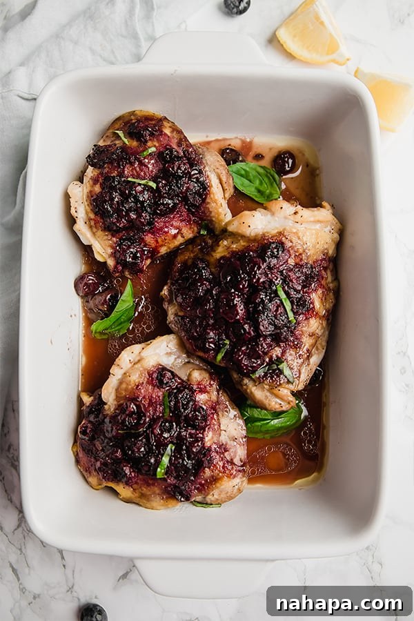 Sweet-Tart Blueberry Balsamic Chicken Thighs 4 Close-up of baked chicken thighs with blueberry balsamic glaze in an oven-safe dish.