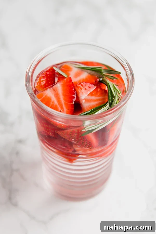 Close-up of three glasses of different infused water flavors: strawberry rosemary, lemon mint, and blueberry basil.