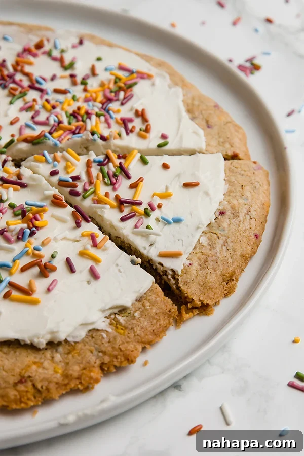 Overhead view of a beautifully decorated funfetti cookie pizza with generous frosting and sprinkles, ready for a celebration.