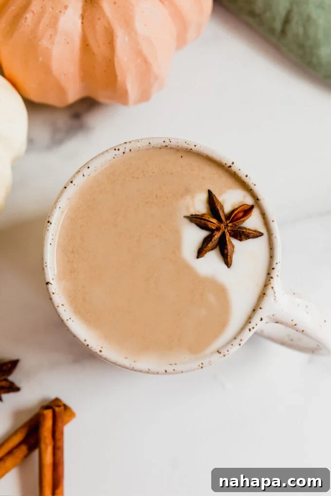A steamy Chai Pumpkin Spice Latte topped with coconut cream and star anise, ready to be enjoyed as a coffee-free, dairy-free, Paleo, and AIP-friendly fall drink.