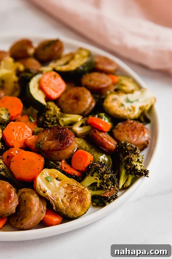 Effortless Sheet Pan Sausage and Veggies Paleo Whole30 Gluten Free 4 A plate featuring a delicious serving of one-pan roasted sausage and vegetables, garnished with fresh parsley.