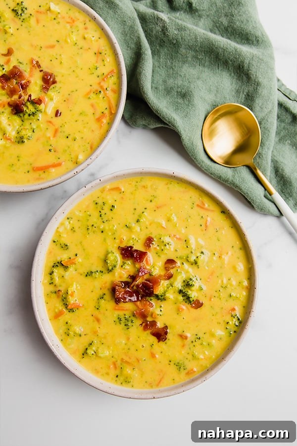 Two bowls of broccoli cheese soup with a green napkin