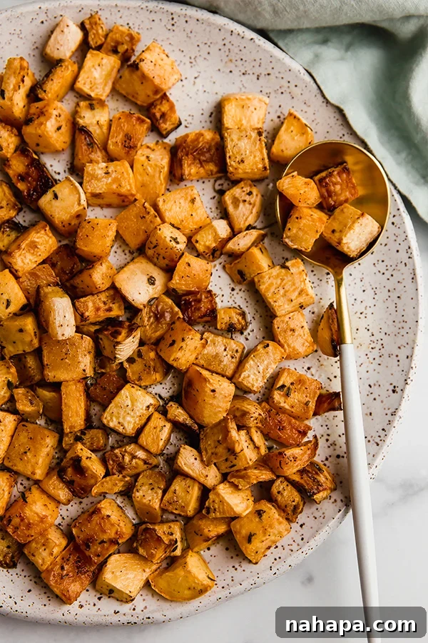 Golden brown oven-roasted rutabaga pieces arranged on a rustic plate, garnished with fresh thyme leaves.