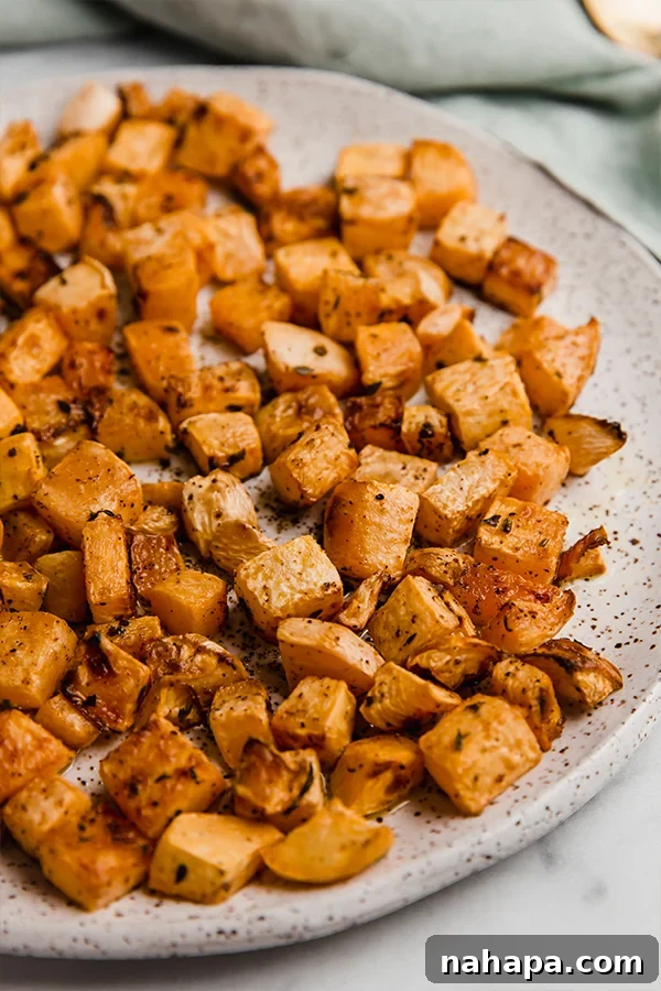 Close-up of golden brown oven-roasted rutabaga on a plate with fresh parsley, ready to serve.