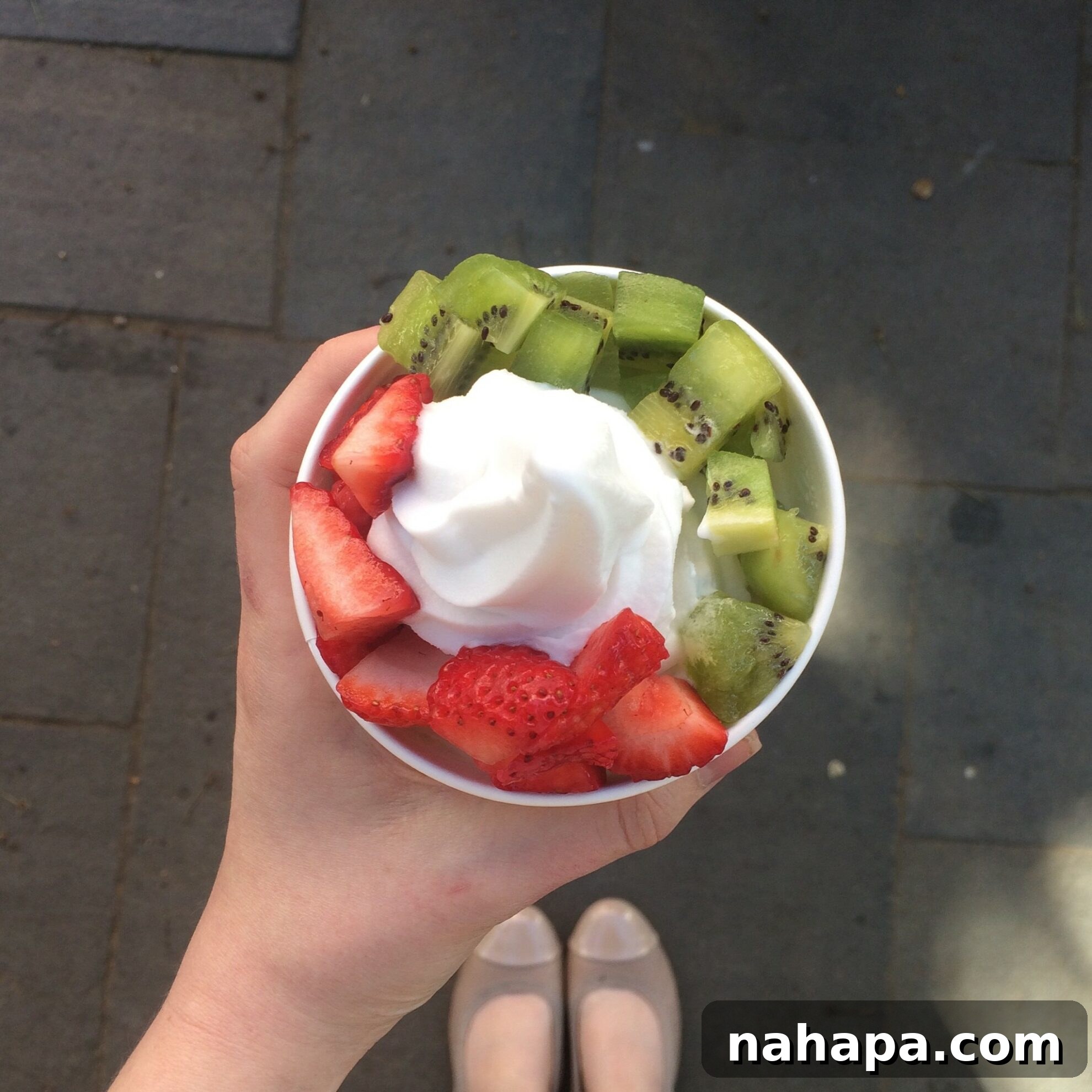 A refreshing dairy-free coconut swirl frozen yogurt from Pinkberry, topped with a vibrant array of AIP-friendly fruits, representing a delightful and safe treat during travel.
