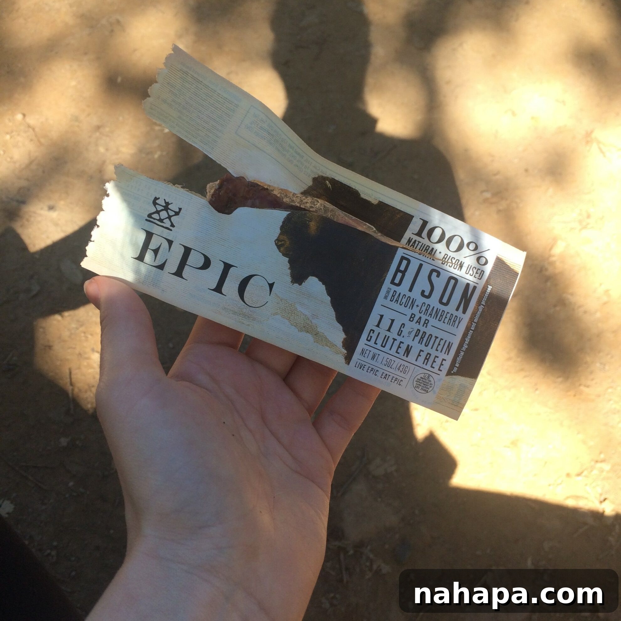A hiker taking a well-deserved break on the strenuous Valley View Trail, enjoying AIP-compliant snacks like an Epic bar and dried mango amidst Big Sur's breathtaking natural beauty, illustrating effective AIP travel fueling.