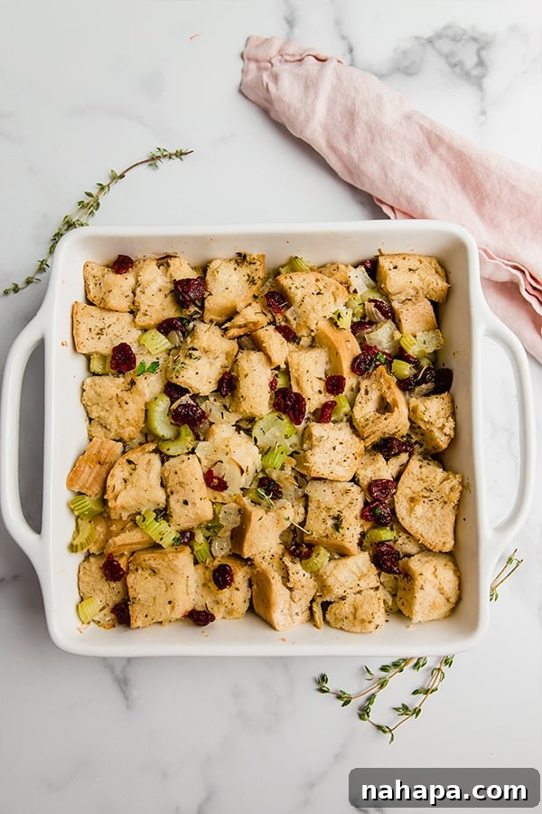 Ultimate Gluten Free Stuffing 4 Close-up shot of golden-brown gluten-free stuffing with visible herbs and cranberries, served in a white casserole dish