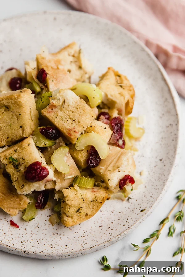 Ultimate Gluten Free Stuffing 5 A beautifully presented serving of golden-brown gluten-free sourdough stuffing on a white plate, garnished with fresh herbs