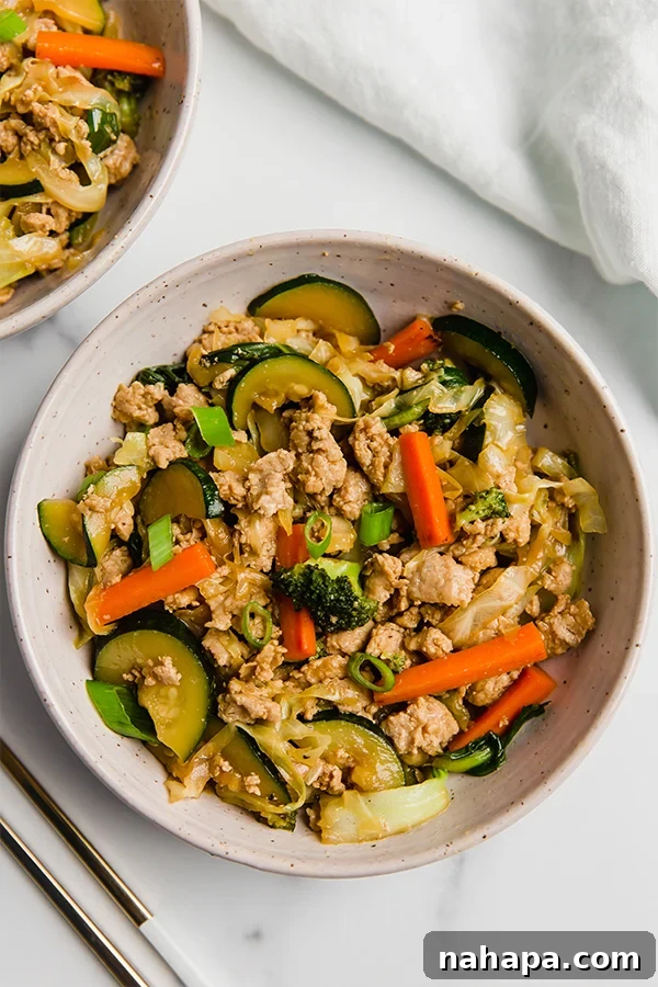 Ground Turkey and Vegetable Teriyaki Stir Fry on a white plate, garnished with green onions and sesame seeds.
