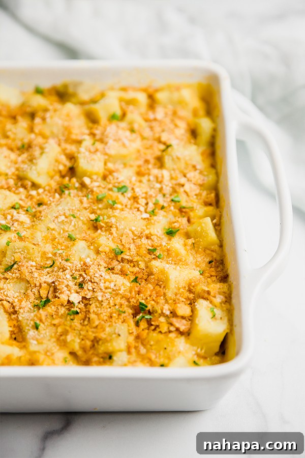 A close-up of a serving of cheesy sweet potato casserole, emphasizing its creamy texture and fresh parsley garnish.