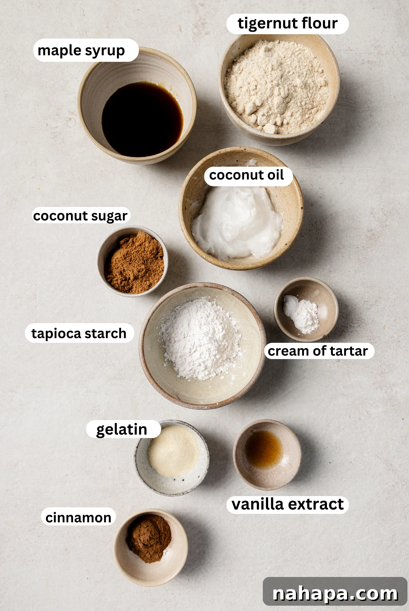 Separate bowls displaying the individual ingredients required for making Snickerdoodle cookies, including flours, sweeteners, and spices.