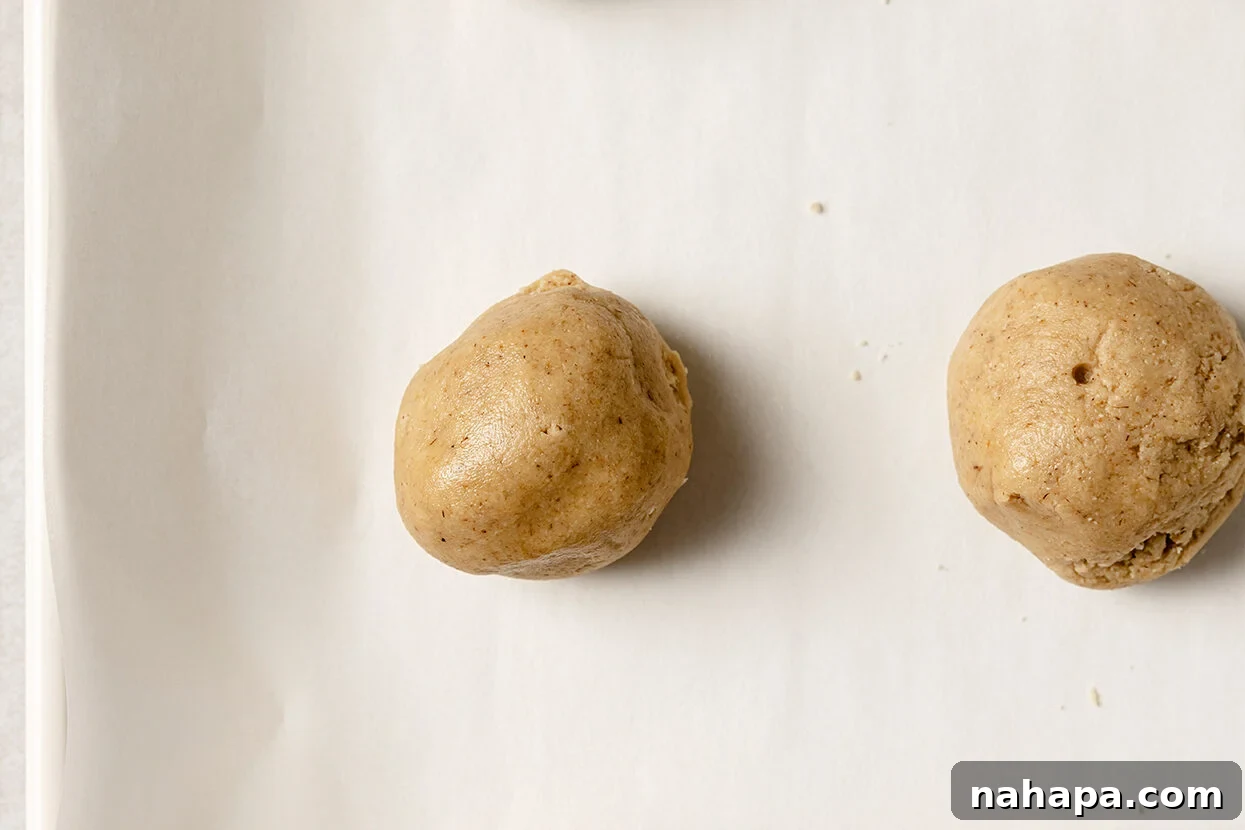 Small, uniform balls of snickerdoodle dough neatly arranged before being coated in cinnamon sugar.